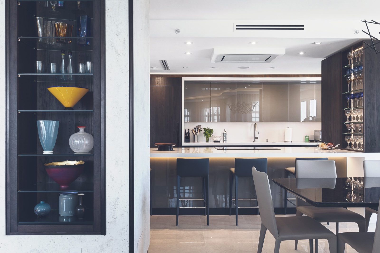 Interior condo remodel in Las Olas Beach, Fort Lauderdale — dark joinery, backlit shelving, and a sculpted kitchen island