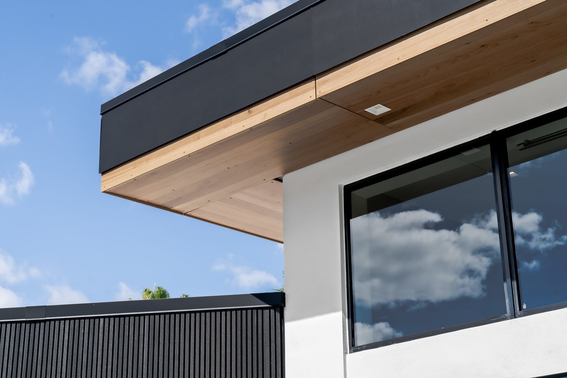 Roofline detail at the Wise Residence — natural wood soffit meeting black fascia against the sky